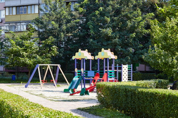 Colorful playground on yard with no children in Kyiv, Ukraine. Play yard with slide, swings and other playground elements. Urban neighborhood childhood concept