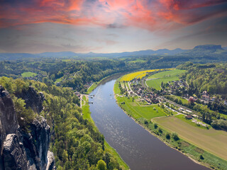 Fototapeta premium aerial view of rural village rathen in the elbe sandstone mountains in east germany with the river elbe from the bastei area with sunset