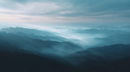 Fototapeta premium A majestic mountain range shrouded in ethereal mist and soft morning light creating a serene and atmospheric landscape