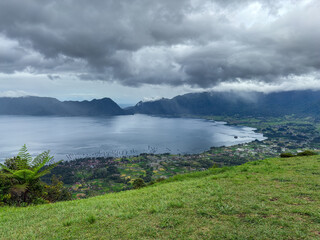 Scenic view of Lake Maninjau surrounded by green hills, captured from Puncak Lawang, a famous tourist destination in Agam, West Sumatra, Indonesia