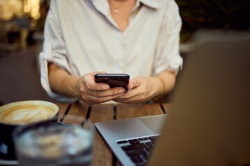 Casual Business Woman Using Smartphone At Outdoor Café With Laptop And Coffee