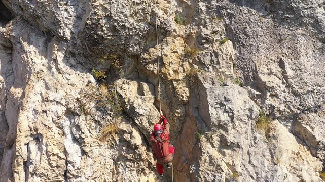  Flying near a mountain rescuer rappelling on a rocky wall with a drone