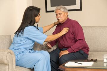 Obraz premium Indian home care nurse checking senior male heart beat checkup through stethoscope at home. 