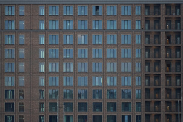 Modern apartment building facade featuring multiple rows of identical windows with some open and closed, showing repetitive architectural pattern and urban residential structure