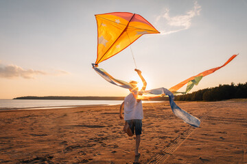 Boy running with kite on beach at golden hour, dynamic ribbons,