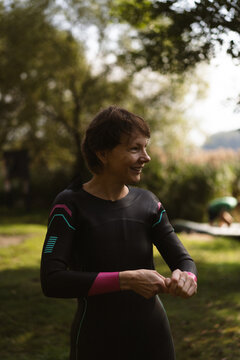 Smiling woman in a wetsuit preparing for water sports outdoor