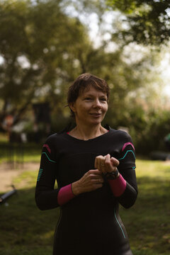 Smiling woman in a wetsuit preparing for water sports outdoor
