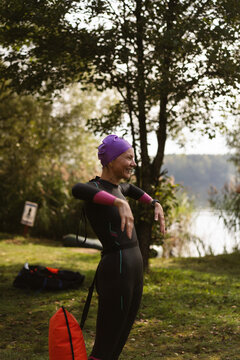 Smiling woman in a wetsuit preparing for water sports outdoor