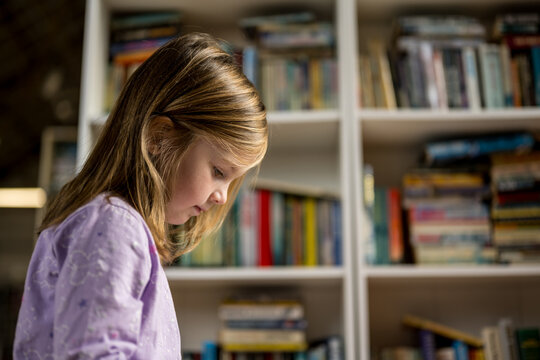 Little girl reading book in the library, book shop