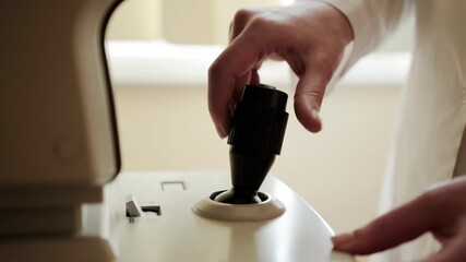 The hand of an ophthalmologist controls the joystick of an ophthalmological device Autorefractometer. Checking the patient's vision, close-up