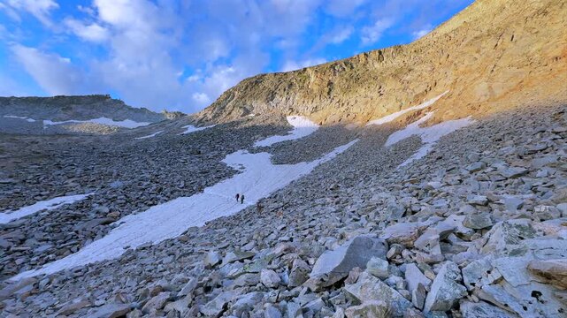 Hikers walking snow glacier melt Capitol Peak Trailhead Ridge route Mt Daly K2 Colorado Rocky Mountain Elk Range landscape sunrise morning high alpine elevation Aspen Snowmass Wilderness pan left