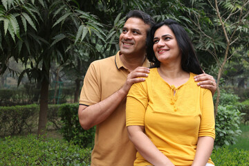 Fototapeta premium Indian young lovely couple hugging outdoors at the nature. Portrait of happy young indian couple fun together, husband wife morning walk outdoor. enjoying summer day outdoors. 
