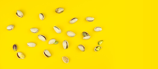 scattered pistachio kernels on bright yellow background with blank space for ad, text or graphics 