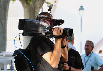 Cámara TV enfocando y grabando con cámara profesional al hombro en directo para programa audiovisual de televisión