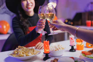 Friends celebrating halloween party toasting wine glasses