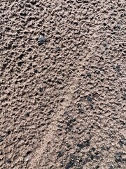Dry sandy ground with scattered rocks and footprints. Natural texture background useful for design, construction, environment, geology, and outdoor nature concepts.