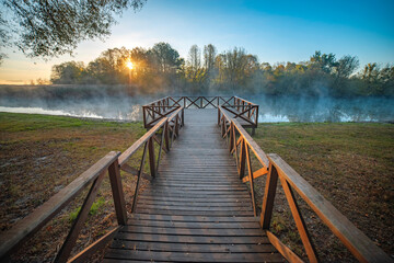 Autumn park by the river with fog.