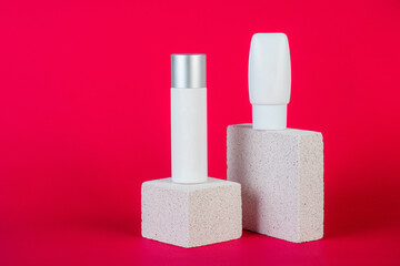 Cosmetic product in tube, bottle, lotion or serum with stylish props on red background. 