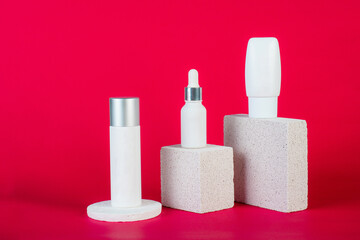 Cosmetic product in tube, bottle, lotion or serum with stylish props on red background. 