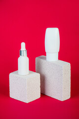 Cosmetic product in tube, bottle, lotion or serum with stylish props on red background. 