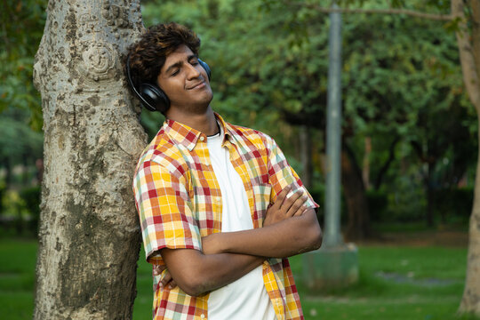 Indian student listening to music with wireless earphones, using mobile phone. dressed in casual clothing. Teenagers lifestyle concepts