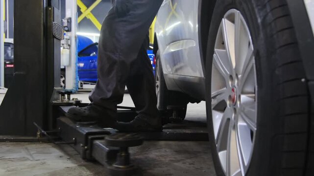 Man prepares to activate vehicle position fixation mechanism. Mechanic adjusts leg of structure and touches structure with foot moving construction