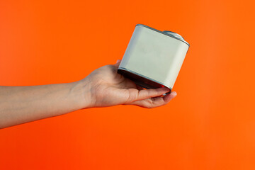 White can for packaging in hand on orange background.