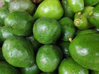 Pile of fresh avocados displayed at local farmers market showcasing vibrant green hues and smooth textures, offering a healthy and delicious food choice.