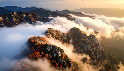 Mountain Peaks Surrounded by Clouds at Sunset with Colorful Foliage