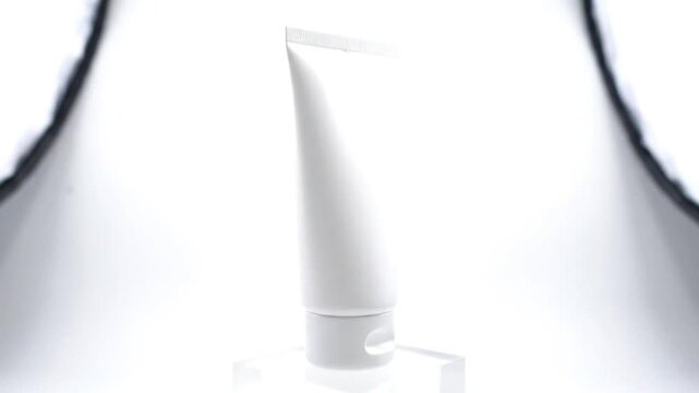 A minimalist white tube, perfect for showcasing cosmetic or skincare products, stands elegantly illuminated in a bright studio setting, emphasizing its clean design.