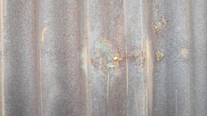 Corrugated metal sheet shows signs of rust and weathering outdoors, creating a textured and aged surface with industrial character.