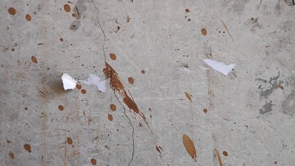 Concrete floor shows signs of wear with splatters and scraps in an abandoned building, creating a...