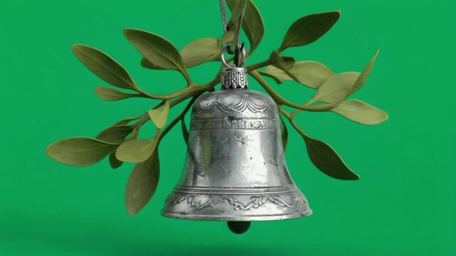 Silver bell ornament hanging with mistletoe on a green screen for christmas holiday celebration christmas bell green screen video