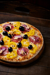 Pizza with chorizo ​​sausage, mozzarella cheese and yellow pepper. Rustic wooden background. Soft focus.	