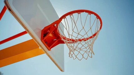 Basketball hoop against blue sky ideal for sports graphics, athletics promotion, inspirational content, basketballthemed designs, and outdoor activities branding.