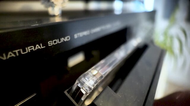 Hand inserting audio cassette tape into a retro stereo hifi sound system