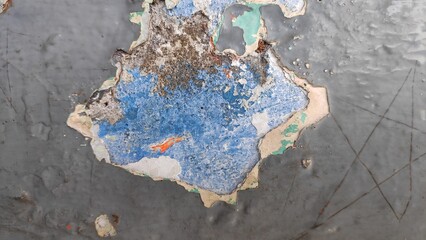 Peeling paint reveals layers of color on an old wall, creating a textured and weathered surface with an abstract and grungy aesthetic.
