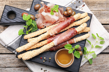 Grissini breadsticks with prosciutto, olives and honey on wooden table, top view