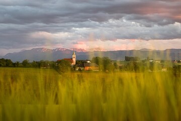 Village church with fields and mountains at sunset in Upper Austria