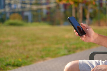 Person holding smartphone outdoors on bench