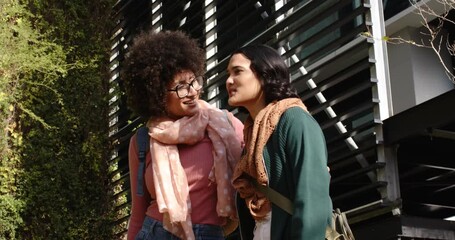 Diverse female friends posing for shot on path laughing talking waving with backpacks  and  scarves
