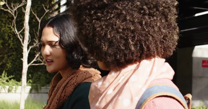 Diverse female friends wearing backpacks on bench outside, speaker explaining concern after glance