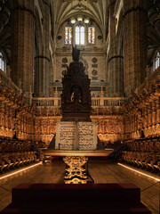 Choir and ancient music book in Salamanca cathedral. Ornate choir stalls and giant choir book in Salamanca cathedral, with wood carvings and stained glass windows