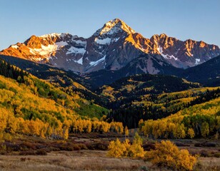 Majestic mountain peak bathed in golden sunrise light, autumn foliage