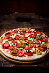 Pizza with salami, jalapeno pepper, cherry tomatoes and mozzarella cheese. Soft focus.	