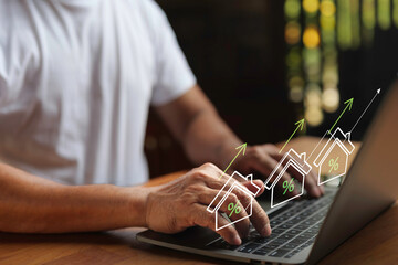 Man using laptop with rising house icons and percentage signs, symbolizing real estate investment, housing market growth, mortgage rates, and property business success.