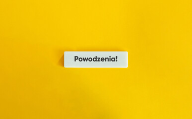 Powodzenia napis na białym kafelku na żółtym tle