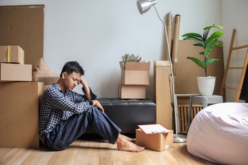 Frustrated Man Sitting on Floor with Head in His Hands Surrounded by Moving Boxes