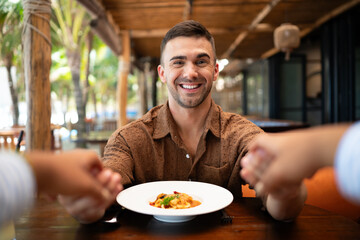 Dining experience, a smiling man shares happiness and food at the table, laughter and togetherness