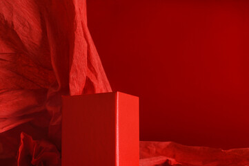Empty red podium on dramatic red background with crumpled paper